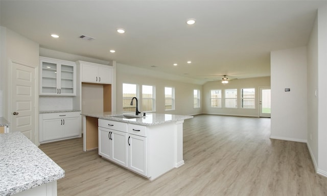 kitchen featuring white cabinets, ceiling fan, sink, and a kitchen island with sink