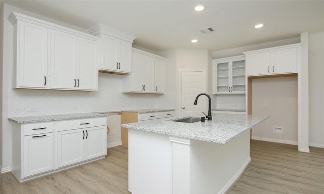 kitchen featuring white cabinets, sink, and a kitchen island with sink