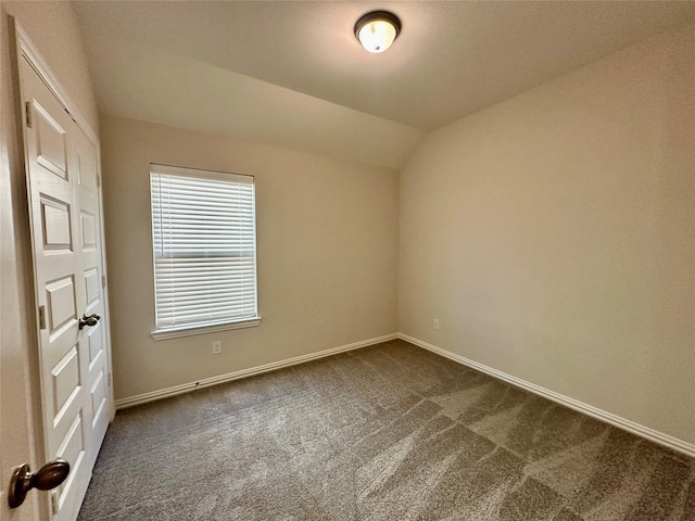 empty room featuring dark carpet and lofted ceiling