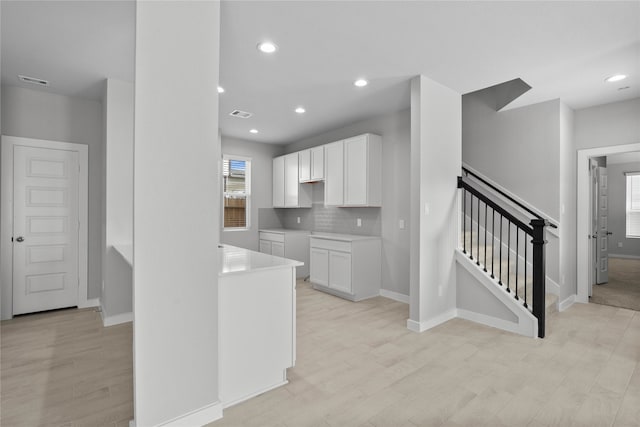 kitchen with a wealth of natural light, white cabinets, and light wood-type flooring