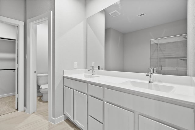 bathroom featuring hardwood / wood-style floors, vanity, an enclosed shower, and toilet