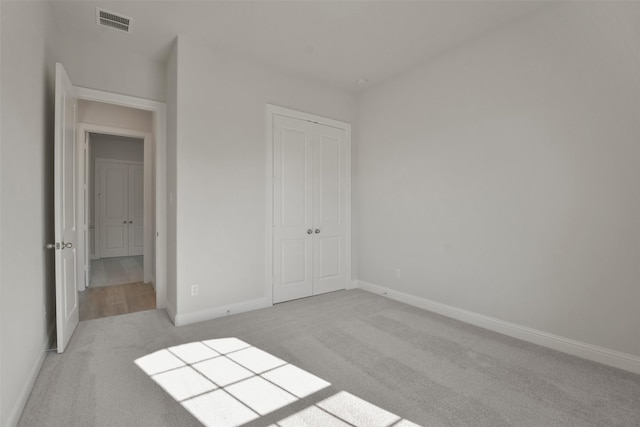 unfurnished bedroom featuring light colored carpet and a closet