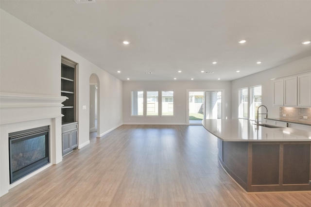 kitchen with built in shelves, a large island, sink, light hardwood / wood-style flooring, and white cabinets