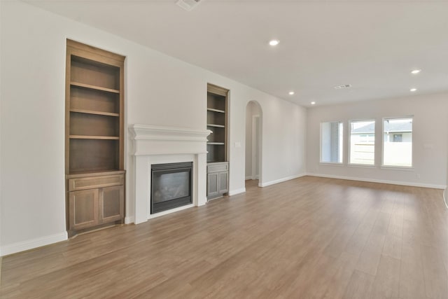 unfurnished living room featuring hardwood / wood-style floors and built in features