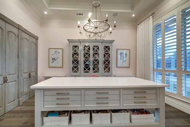 interior space featuring a center island, crown molding, a tray ceiling, decorative light fixtures, and wood-type flooring