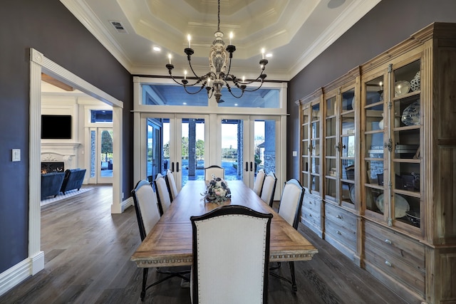 dining area with a raised ceiling, dark hardwood / wood-style flooring, ornamental molding, and french doors