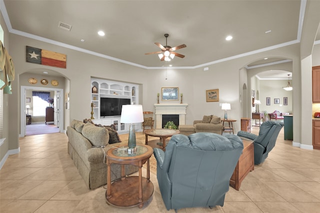 living room featuring ceiling fan, built in shelves, ornamental molding, and light tile patterned floors