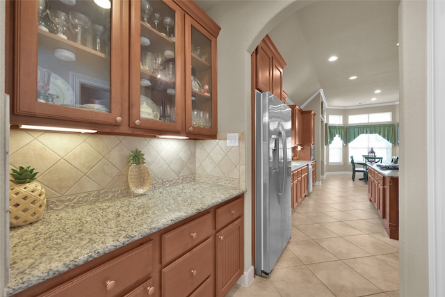 kitchen featuring stainless steel fridge with ice dispenser, light tile patterned flooring, and backsplash