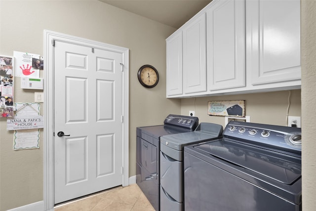 washroom featuring washing machine and clothes dryer, light tile patterned floors, and cabinets