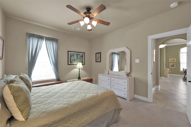 bedroom featuring ceiling fan, light carpet, and multiple windows