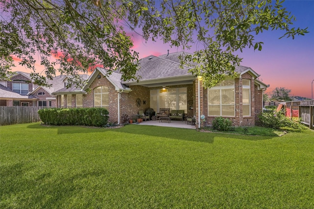 rear view of house with a patio, fence, brick siding, and a lawn