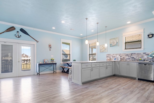 kitchen with stainless steel dishwasher, kitchen peninsula, light hardwood / wood-style floors, decorative light fixtures, and decorative backsplash