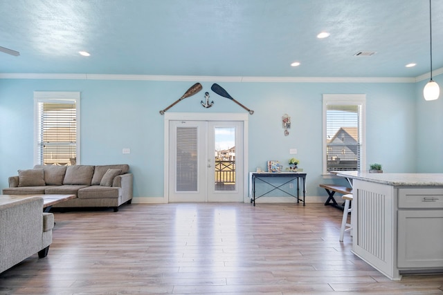 living room with a wealth of natural light, crown molding, and light wood-type flooring