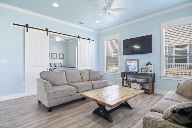 living room with a barn door, ornamental molding, and light hardwood / wood-style flooring