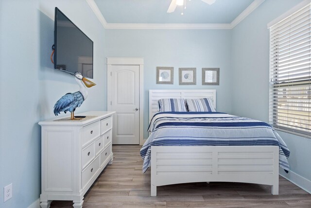 bedroom with light hardwood / wood-style flooring, ceiling fan, and crown molding