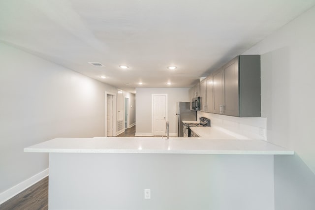 kitchen featuring stainless steel appliances, dark hardwood / wood-style flooring, backsplash, kitchen peninsula, and gray cabinets