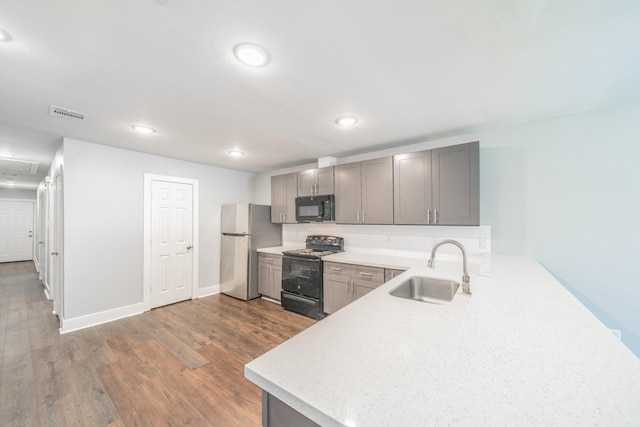 kitchen featuring gray cabinetry, sink, dark hardwood / wood-style floors, backsplash, and black appliances