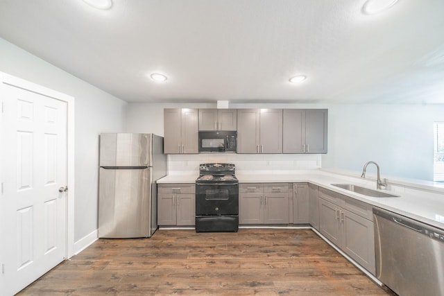 kitchen featuring decorative backsplash, gray cabinetry, dark wood-type flooring, sink, and black appliances