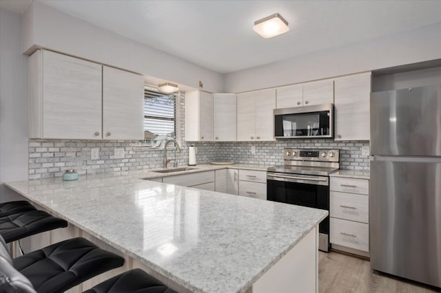 1220 Waterways Dr, Crystal Beach, TX 77650 - kitchen featuring tasteful backsplash, a breakfast bar area, stainless steel appliances, a sink, and a peninsula
