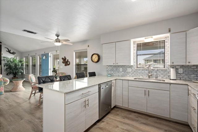 kitchen featuring dishwasher, sink, kitchen peninsula, and light hardwood / wood-style flooring