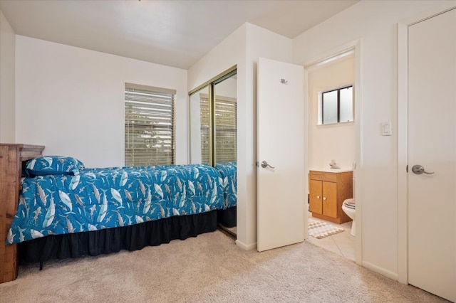 carpeted bedroom with ensuite bathroom, a closet, and multiple windows