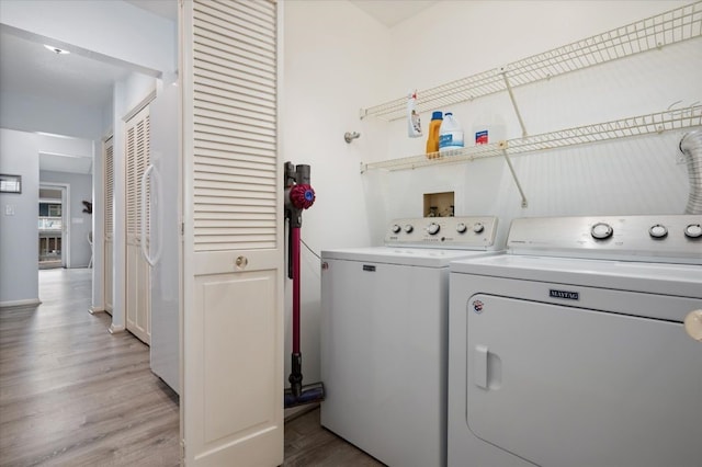 clothes washing area with hookup for a washing machine, washer and dryer, and light wood-type flooring