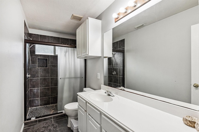 bathroom featuring walk in shower, tile patterned flooring, a textured ceiling, toilet, and vanity