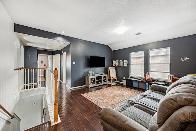 living room featuring a textured ceiling, dark wood-type flooring, and vaulted ceiling