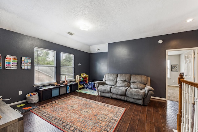 living room with a textured ceiling and dark hardwood / wood-style floors