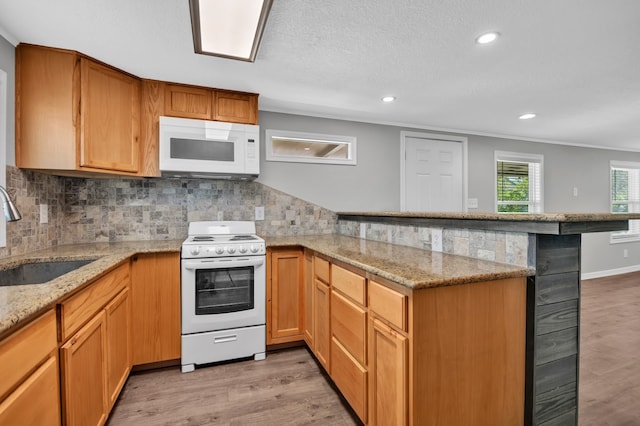 kitchen featuring backsplash, sink, white appliances, and light wood-type flooring