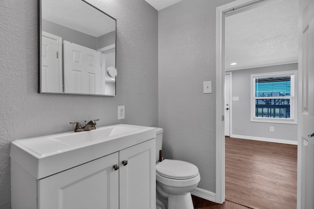 bathroom featuring hardwood / wood-style floors, vanity, toilet, and a textured ceiling