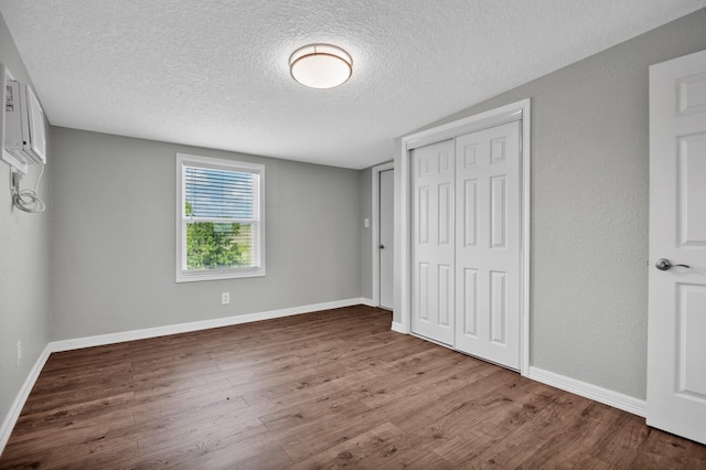 unfurnished bedroom with wood-type flooring, a closet, and a textured ceiling