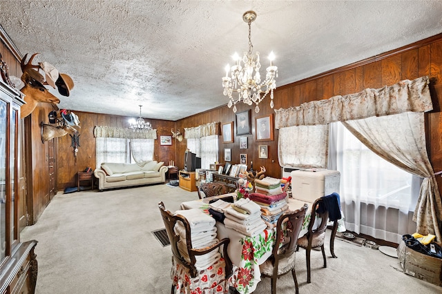 dining area featuring a notable chandelier, light carpet, and wooden walls