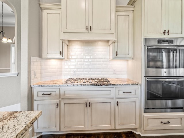 kitchen featuring cream cabinets, appliances with stainless steel finishes, decorative backsplash, and light stone counters