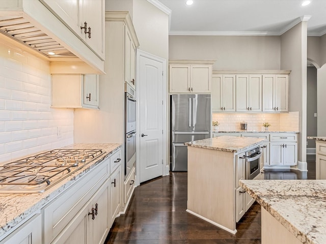 kitchen with light stone counters, crown molding, stainless steel appliances, dark wood-type flooring, and premium range hood