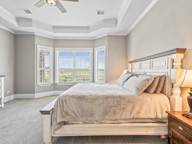 carpeted bedroom with ornamental molding, a tray ceiling, visible vents, and baseboards