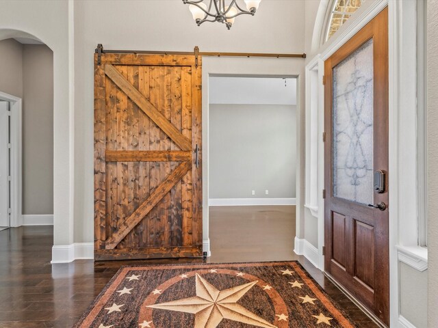 entryway featuring baseboards, arched walkways, a chandelier, and wood finished floors