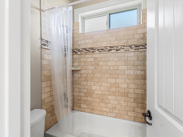 bathroom featuring toilet and shower / tub combo with curtain