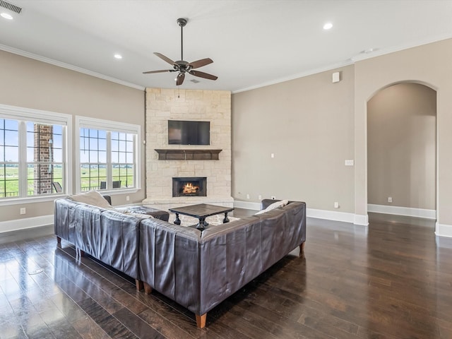 living area with crown molding, a fireplace, arched walkways, and wood finished floors