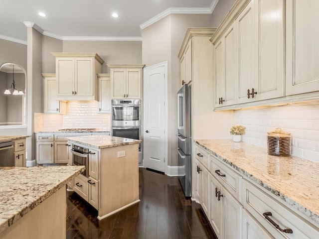 kitchen featuring appliances with stainless steel finishes, light stone counters, cream cabinets, and dark wood-style floors