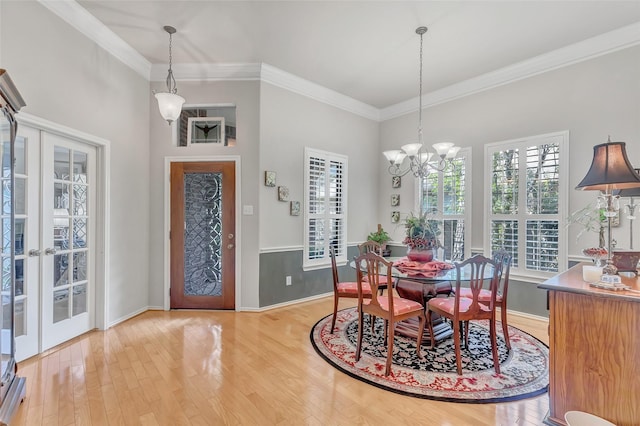 dining space featuring ornamental molding, an inviting chandelier, light wood-type flooring, and french doors