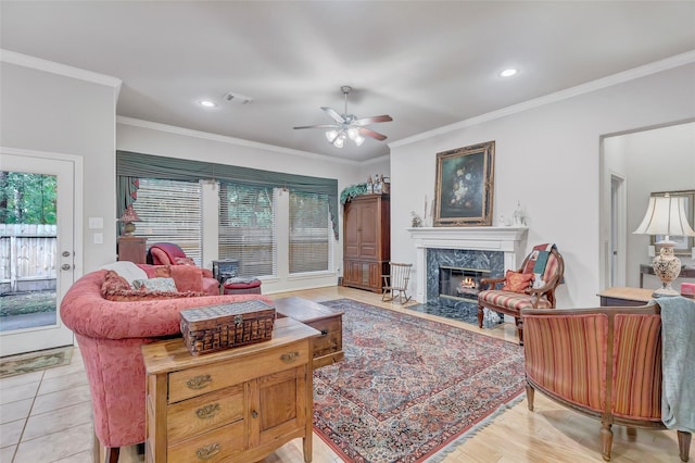 tiled living room featuring a premium fireplace, ornamental molding, and ceiling fan