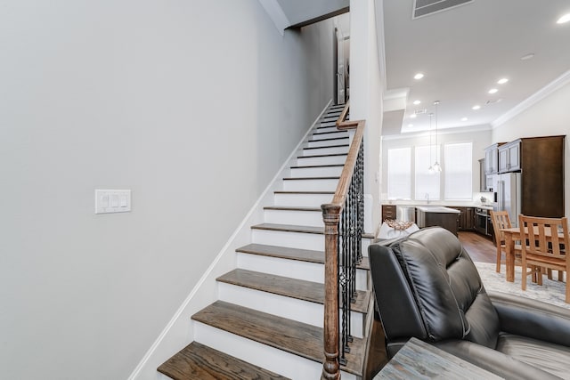 staircase with sink, light hardwood / wood-style floors, and crown molding