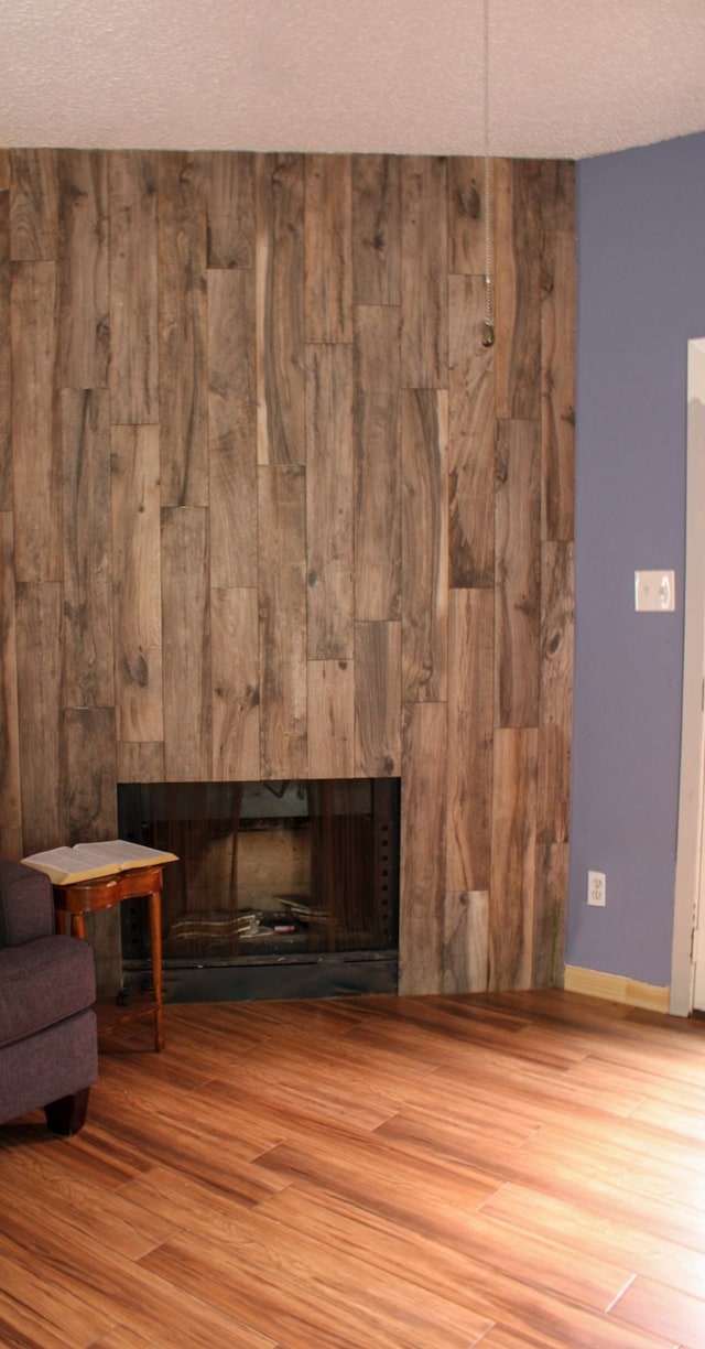 interior space with wooden walls, a textured ceiling, and hardwood / wood-style flooring