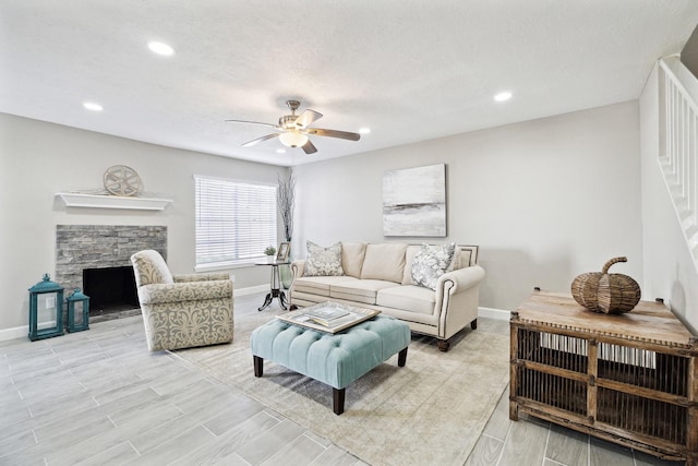 living room with ceiling fan and a stone fireplace