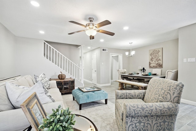 living room with ceiling fan with notable chandelier and light hardwood / wood-style flooring