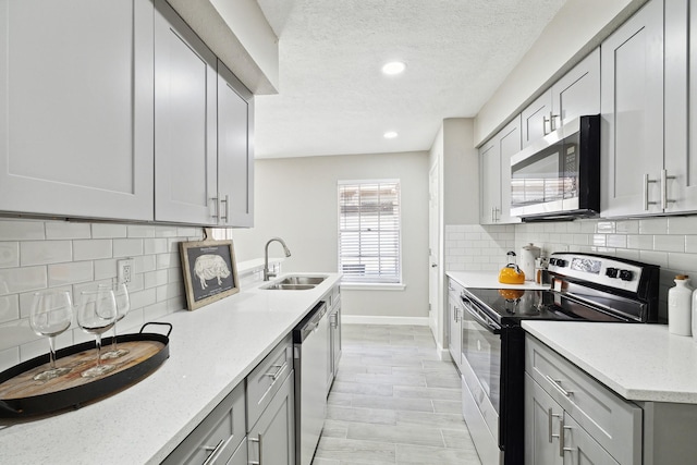 kitchen featuring appliances with stainless steel finishes, tasteful backsplash, light stone counters, and sink