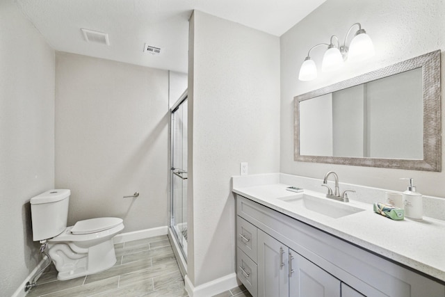 bathroom featuring vanity, toilet, and a shower with shower door