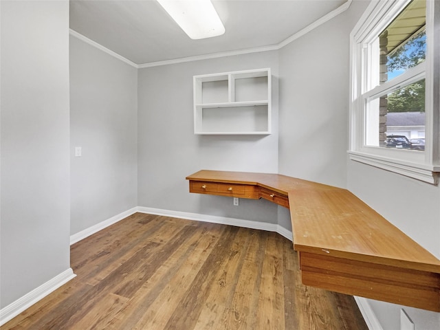 unfurnished office with wood-type flooring, crown molding, and built in desk