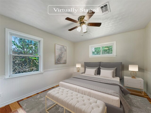 bedroom featuring ceiling fan, multiple windows, and wood-type flooring